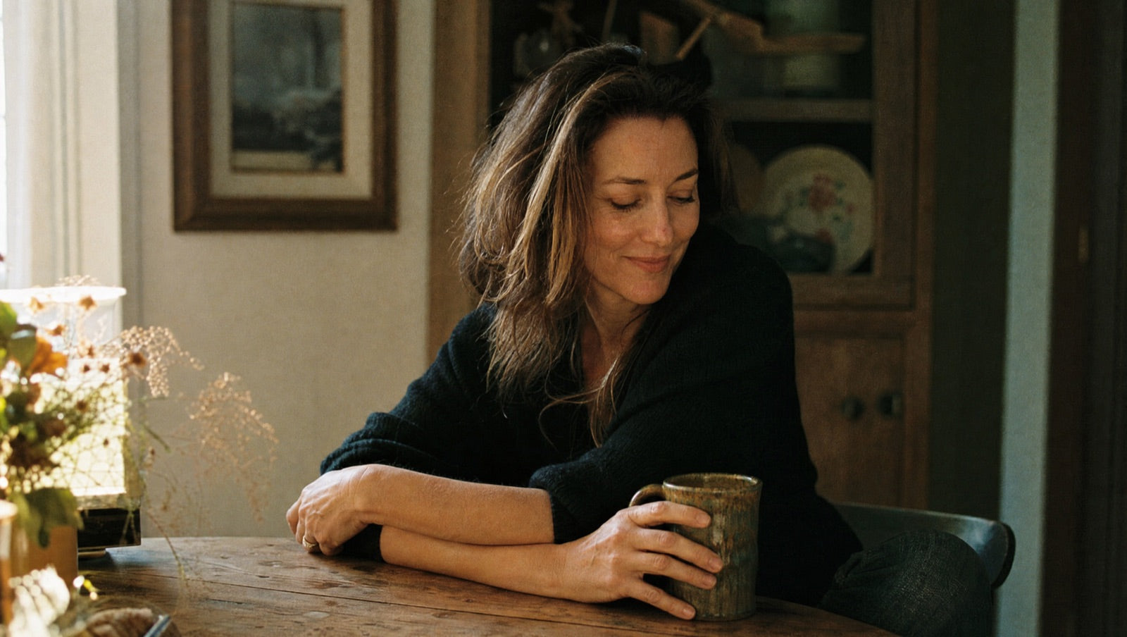 A woman in soft morning light looking calm, kind and self-compassionate, no longer carrying shame